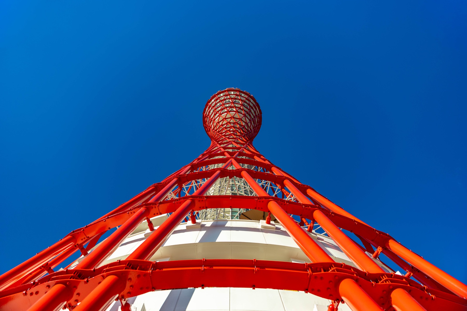 Low-angle view of a red steel tower against a clear blue sky.