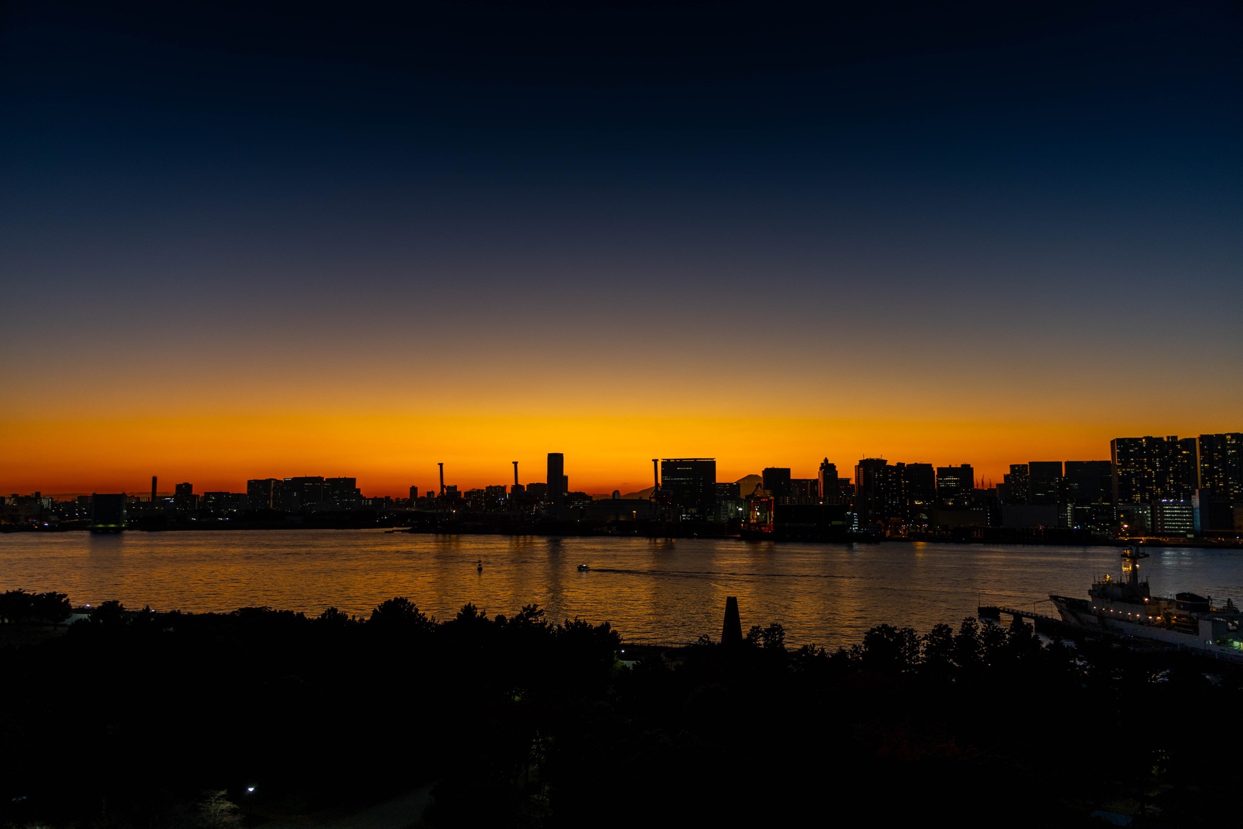 An orange sunset over a waterfront city skyline.