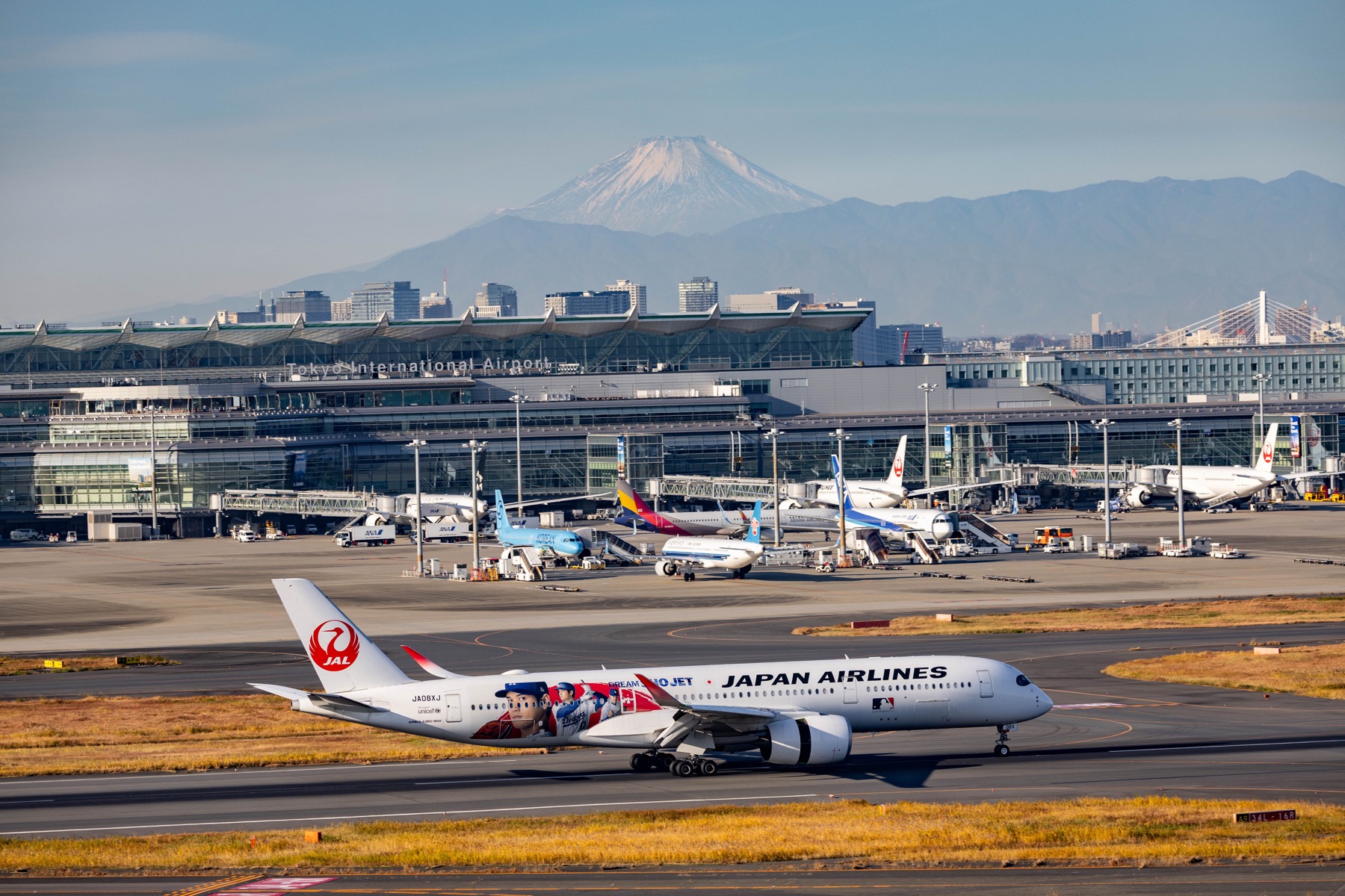 A Japan Airlines plane taxiing with Mount Fuji in the distance.